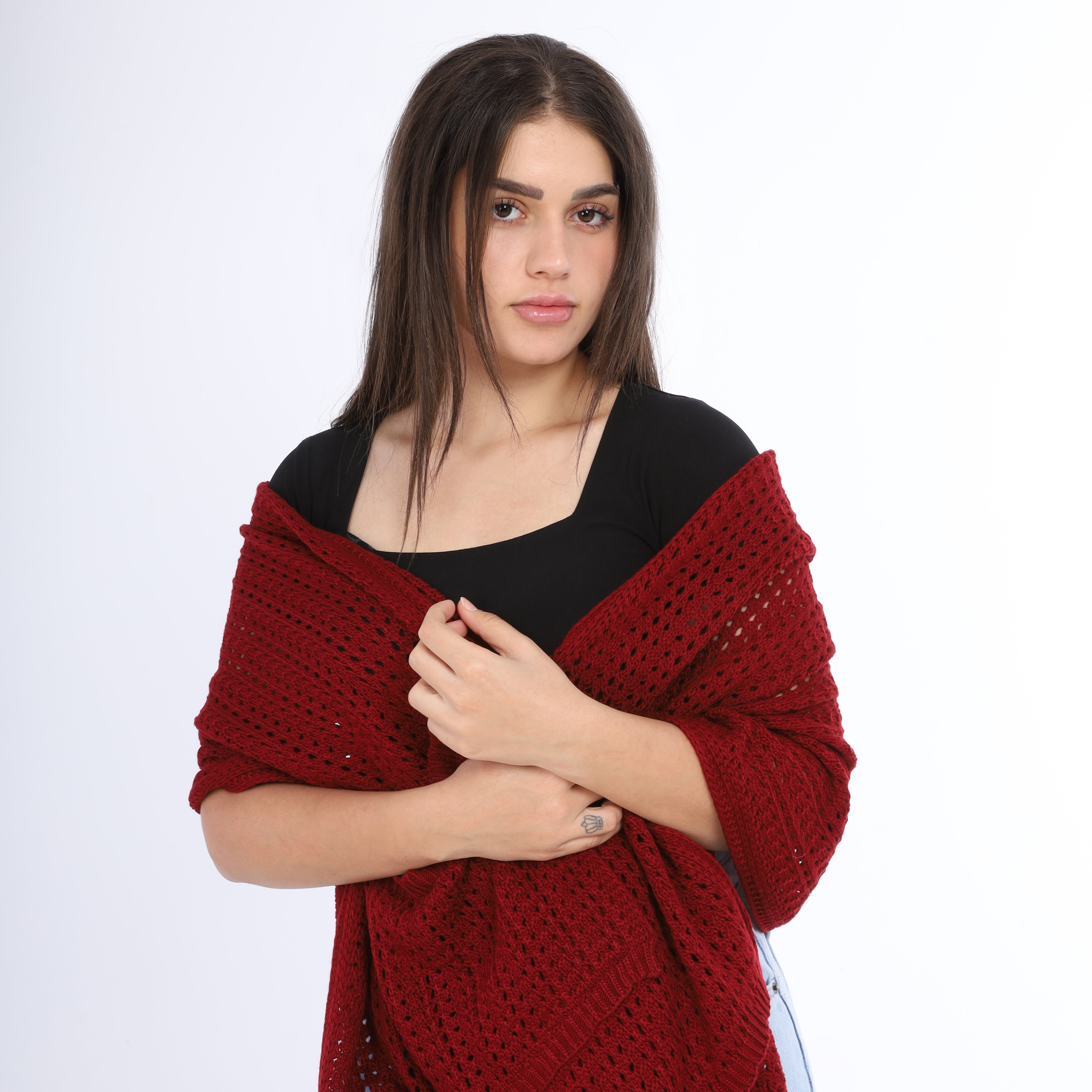 Woman wearing a red knitted shawl over a black top on a white background
