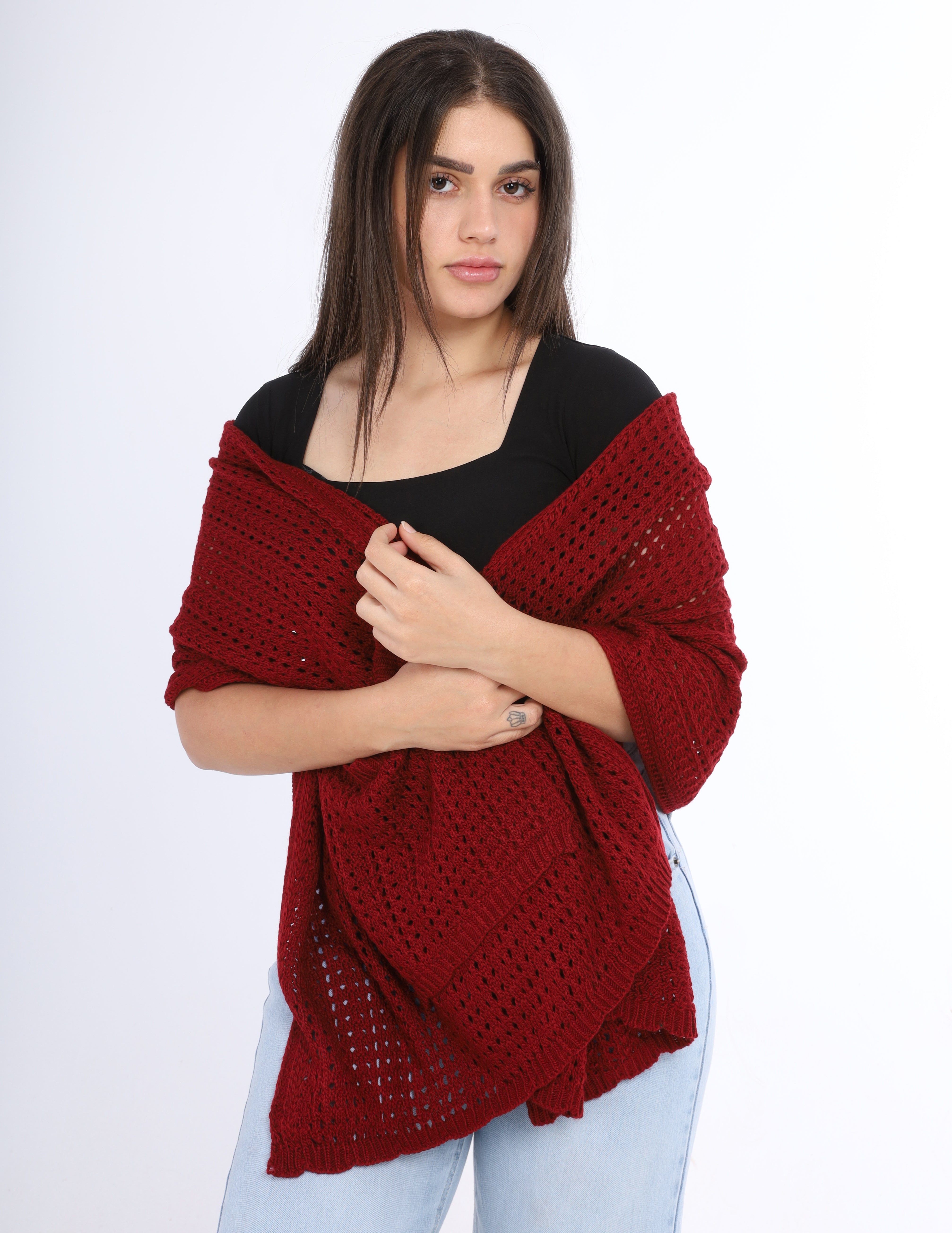 Woman wearing a red knitted shawl over a black top on a white background